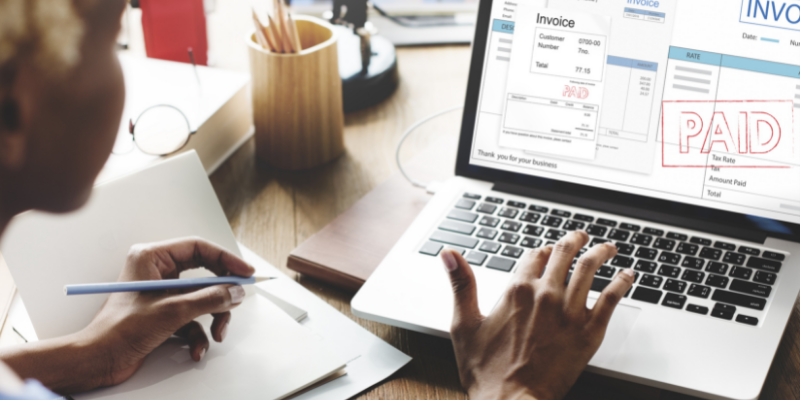 Propietario de negocio revisando sus facturas en su computador.